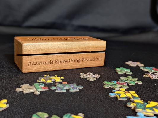 Wooden puzzle box with 'Assemble Something Beautiful' text, surrounded by partially completed puzzles on a dark surface.